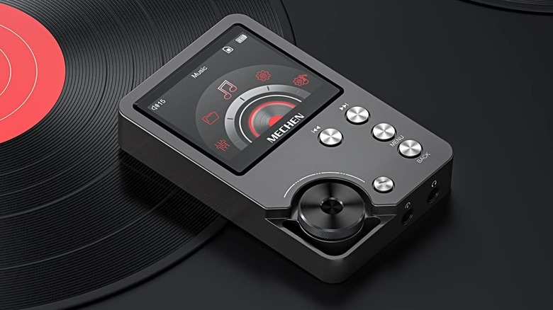 A black Mechen M30 Hi-Fi MP3 Player sitting on top of a vinyl record against a black backdrop,