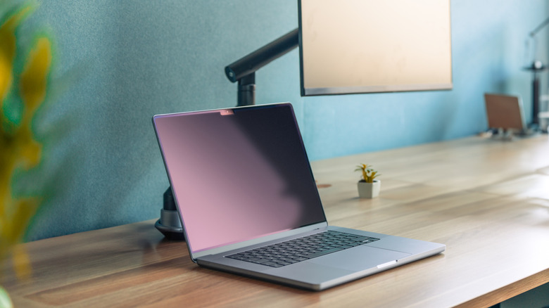 A monitor arm supports a monitor above a laptop computer