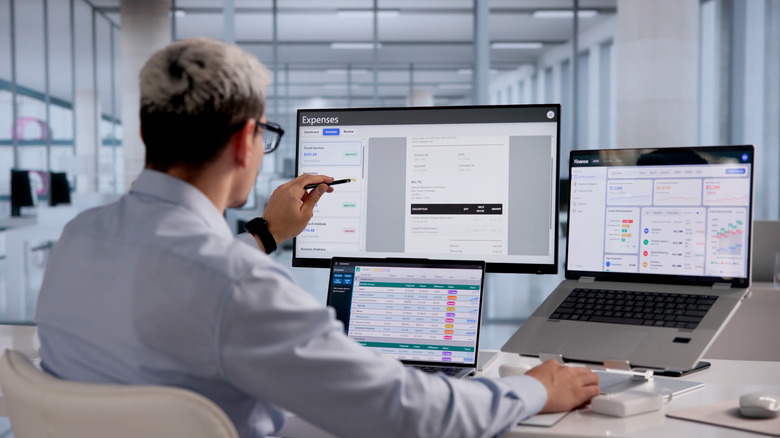 Person working at a desk with a multi-monitor setup showing financial dashboards.