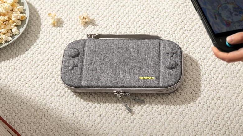 tomtoc switch 2 slim case on carpet rug with switch 2 visible in top-right and popcorn on plate in top-left