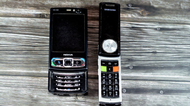 Nokia N95 placed beside another classic phone on a wooden surface.