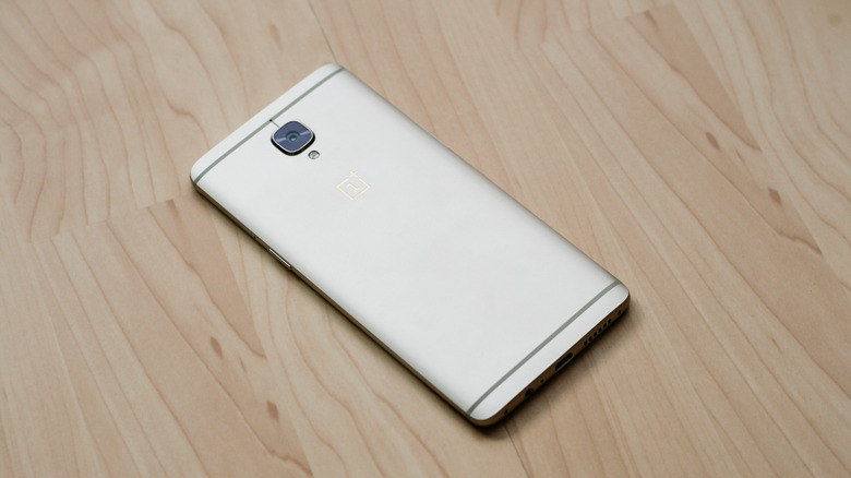 The OnePlus 3 with its metal back facing up on a wooden surface.