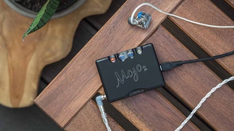 Chord Electronics Mojo 2 resting on wood table with IEMs plugged in