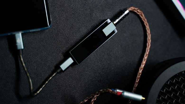 A black DAC plugged into a phone and audio equipment