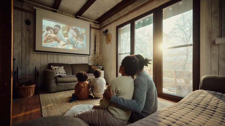 A family watching content on a projector in a room with a lot of ambient light