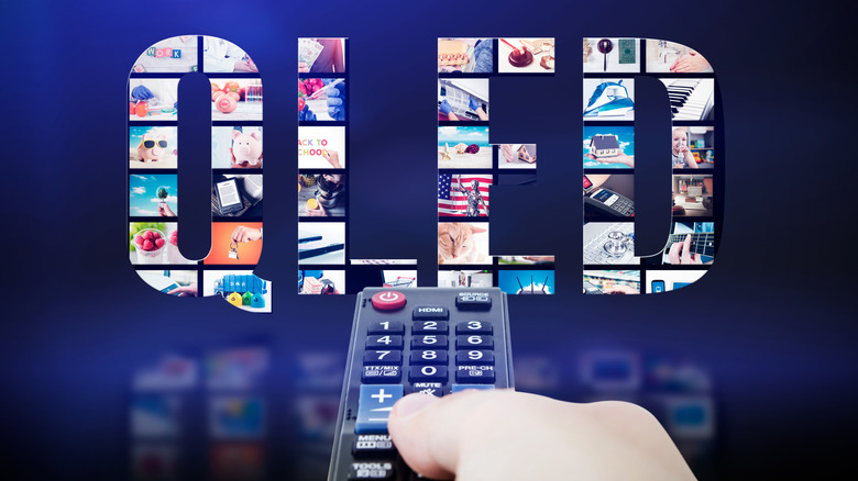 A QLED logo set against a dark backdrop. A person aims a TV remote toward the logo.