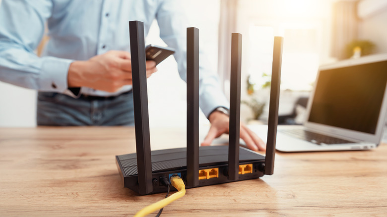 Black wifi router with four antennas. Man using smart phone with fast wireless network