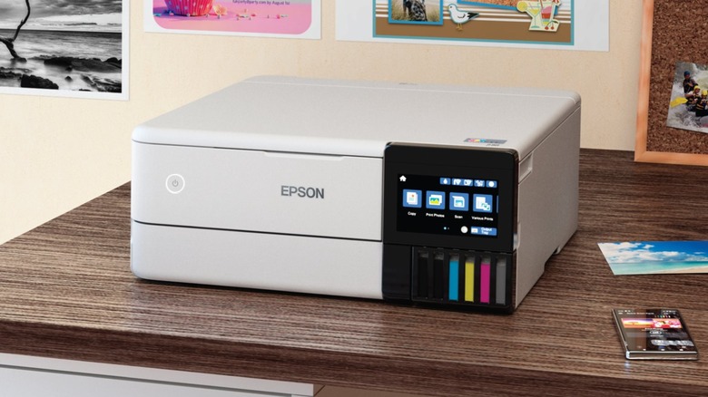A photo of the Epson EcoTank ET-8500 All-in-One Inkjet Printer sitting on a desk, a device that appears to be a cellphone sits next to it