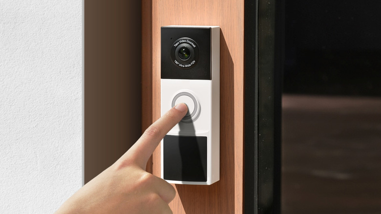 Close-up of a press ringing the Tapo 2K Wireless Smart Video Doorbell D210 mounted on a door