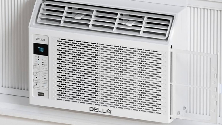 A closeup of a white Della 5,000 BTU Smart Window Air Conditioner sitting in a windowsill