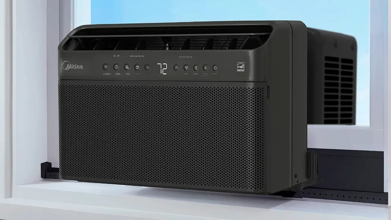 A black Midea U-Shaped Window AC sitting in a white windowsill, the image showcases the device's external controls