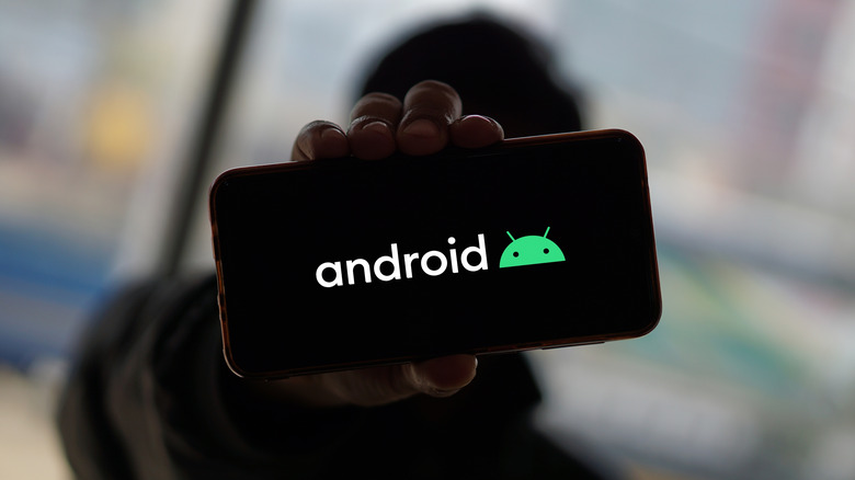 Person holding a phone displaying the Android logo