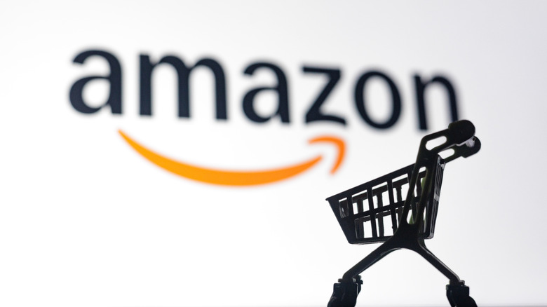 Miniature shopping cart with Amazon logo in the background