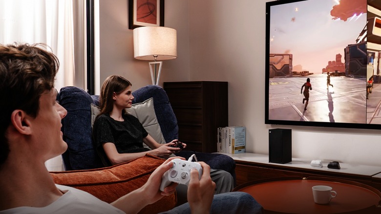 Two people playing couch co-op split screen with GameSir G7 controllers