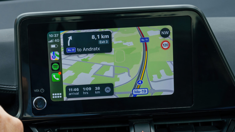 Driver's hand on the wheel with CarPlay displaying a route