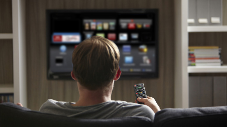Person using a remote control while watching a smart TV.