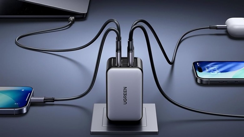 The UGREEN Nexode 65W Wall Charger plugged into an outlet and charging multiple devices