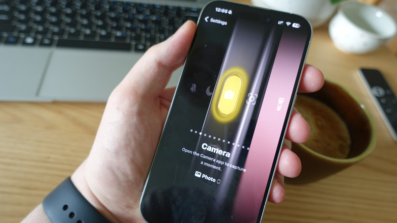 Hand holding iPhone showing Camera option in Action Button settings