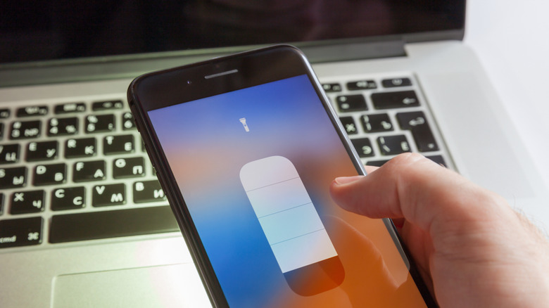Hand holding iPhone showing flashlight option