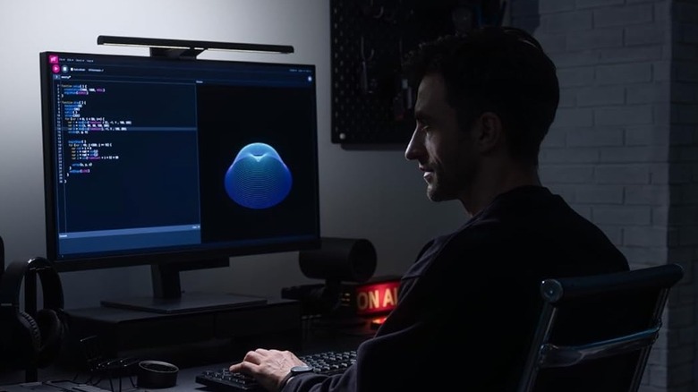 A person working on their computer with a monitor light bar attached to the screen