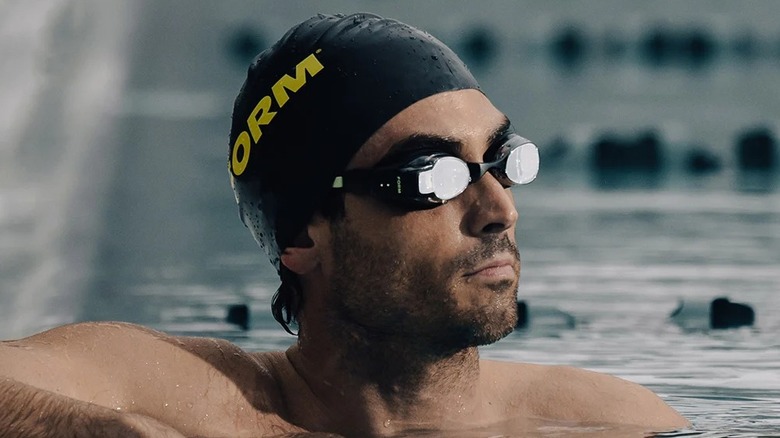 A man in a swimming pool wearing a pair of FORM Smart Swim 2 smart goggles