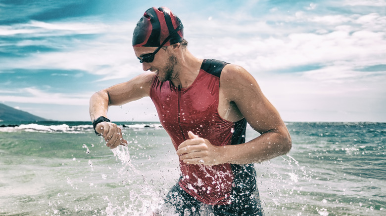 Close up of a man checking a smartwatch while standing in the ocean
