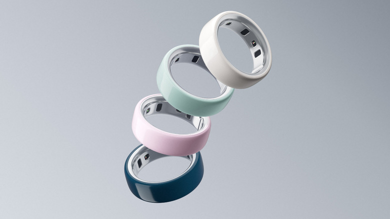 Four Oura Ring 4 Ceramic smart rings of different colors on a gray background.