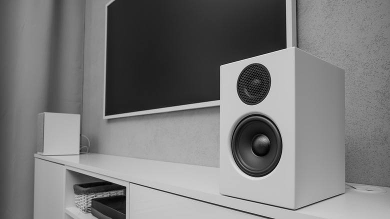 Speaker beside wall-mounted TV in minimalist home theater setup