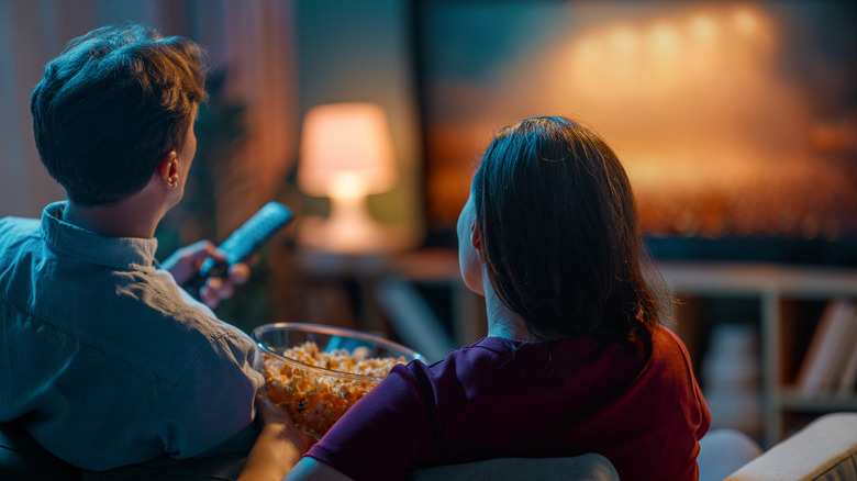 Couple watching TV together with popcorn in cozy home theater setup