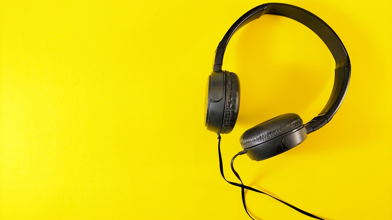 A pair of wired headphones on a yellow background.