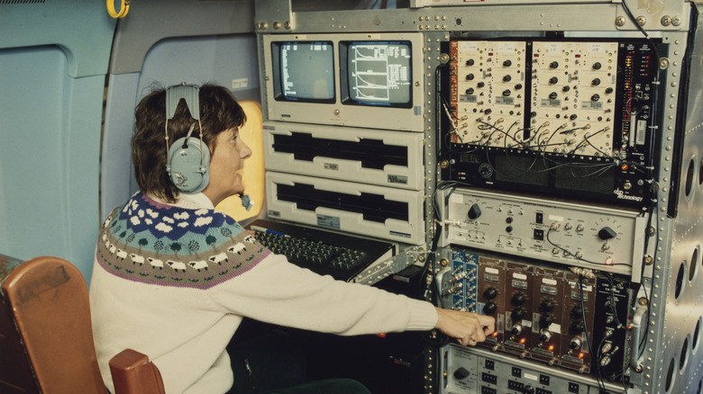 A person working at a complex 1970s computer setup