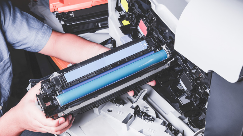 A person installing the toner cartridge in a laser printer