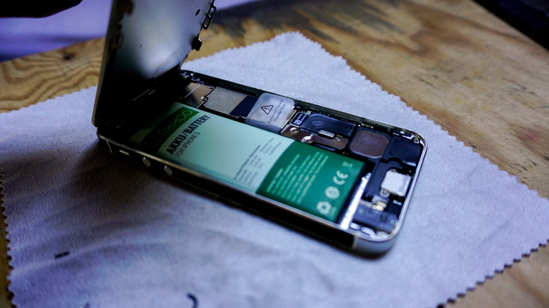 Back panel of an iPhone removed to show its battery during repair