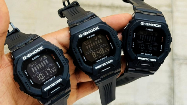 Three black Casio G-Shock digital watches held in hand.