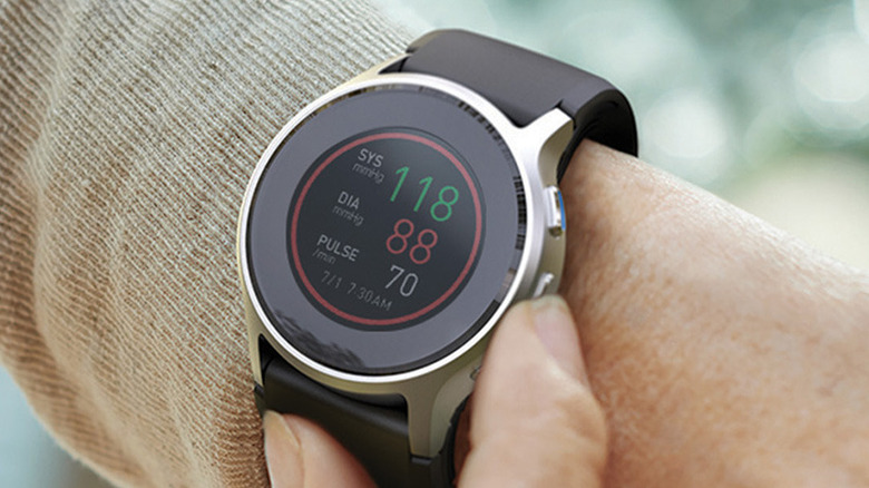 Omron HeartGuide HCR-6900T-M smartwatch showing blood pressure readings on a wrist.