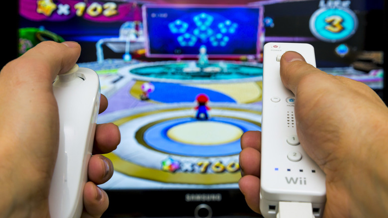 A Wiimote and nunchuck in front of a TV showing Mario Party.