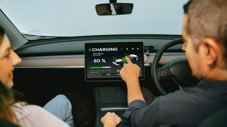 Driver checking EV charging status on touchscreen display inside electric vehicle cabin