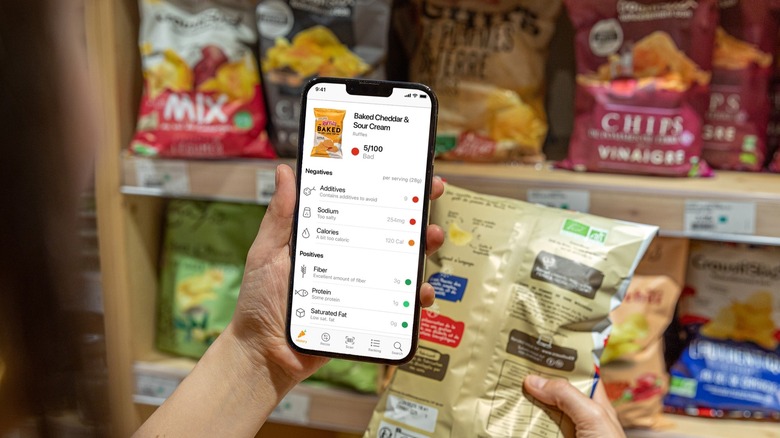 A person using the Yuka app to a scan a packet of chips in a store
