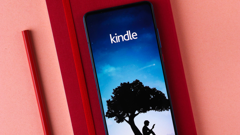 Smartphone showing the Kindle app on top of a red book.