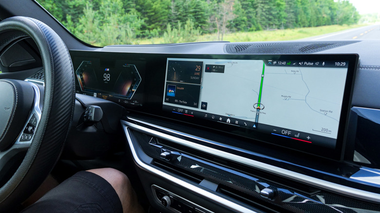 BMW dashboard display showing navigation and driver assistance information while driving on a road.