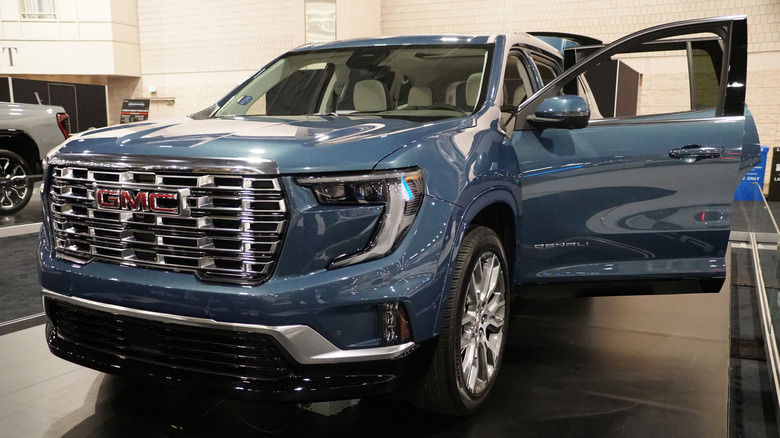 2024 GMC Acadia SUV displayed indoors with the front passenger door open.