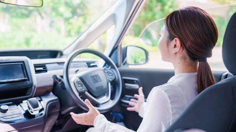 Woman sitting in the driver's seat with her hands off the wheel in a self-driving car.