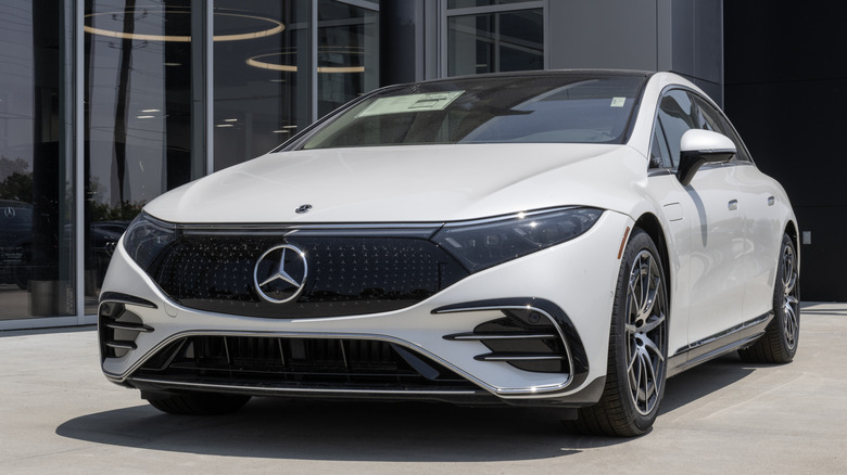 White Mercedes-Benz EQS 580 sedan parked outside a dealership.