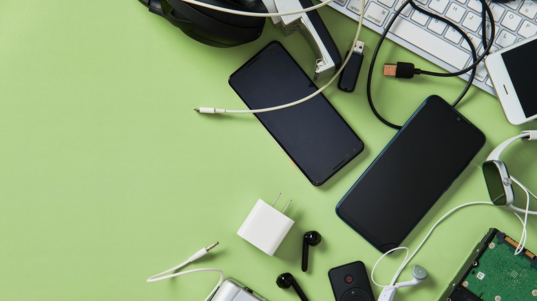 Smartphones, chargers, cables, and gadgets scattered on a desk