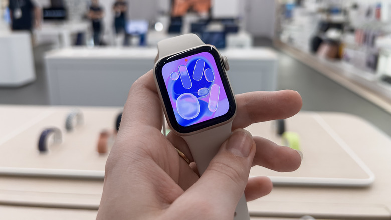 Apple Watch SE 3 held in hand with display turned on.