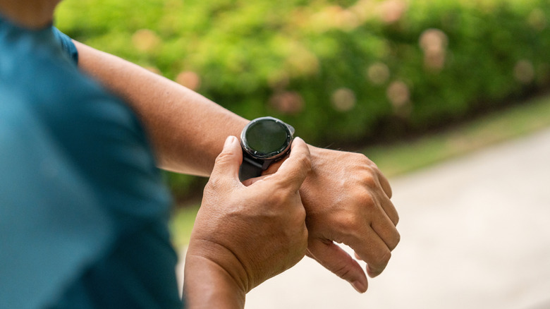 Person checking a smartwatch while outdoors.