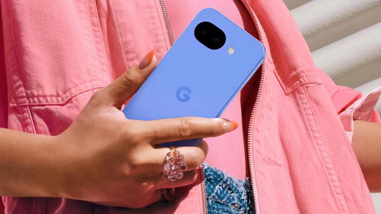 Person holding a blue Google Pixel 10 with the rear camera visible.
