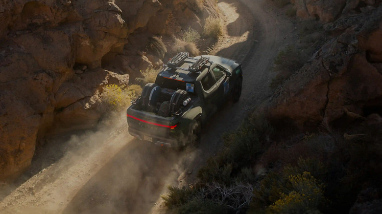 A loaded Rivian R1T driving on a dirt road