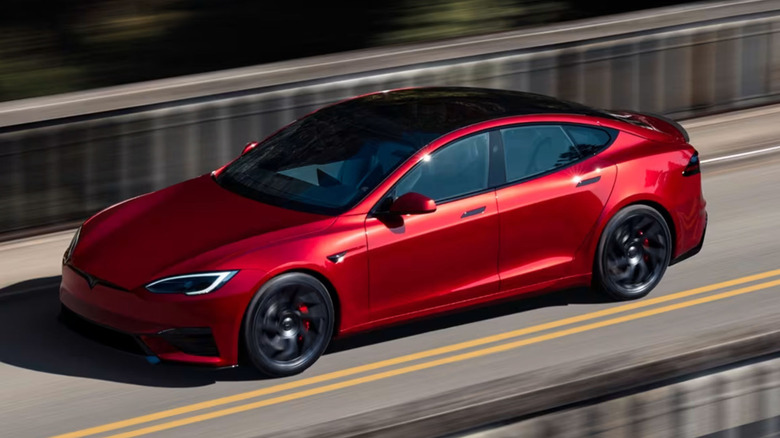 A red Tesla Model S driving across a bridge