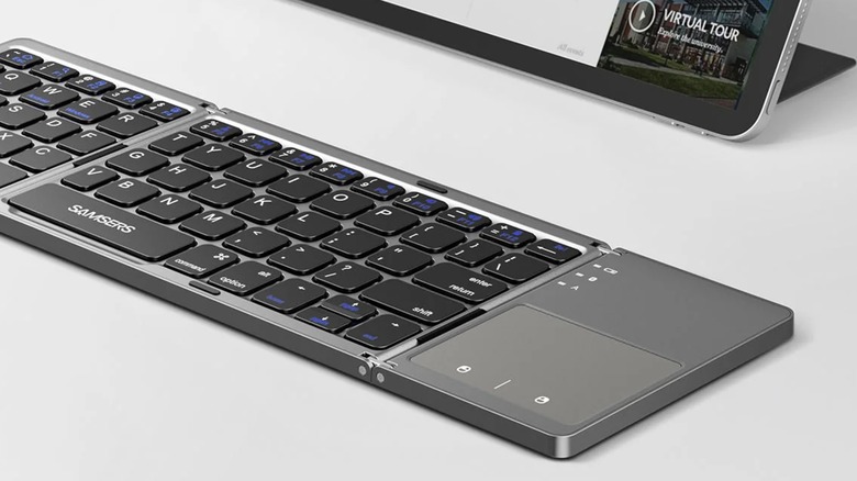 A black Samsers Foldable Bluetooth Keyboard with Touchpad sits on a gray surface